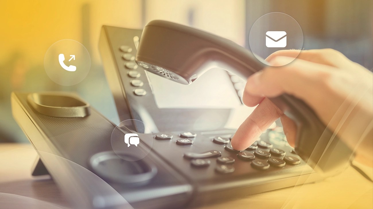 A low-angle view of someone dialing an office phone, representing the professional tools offered through business phone plans.
