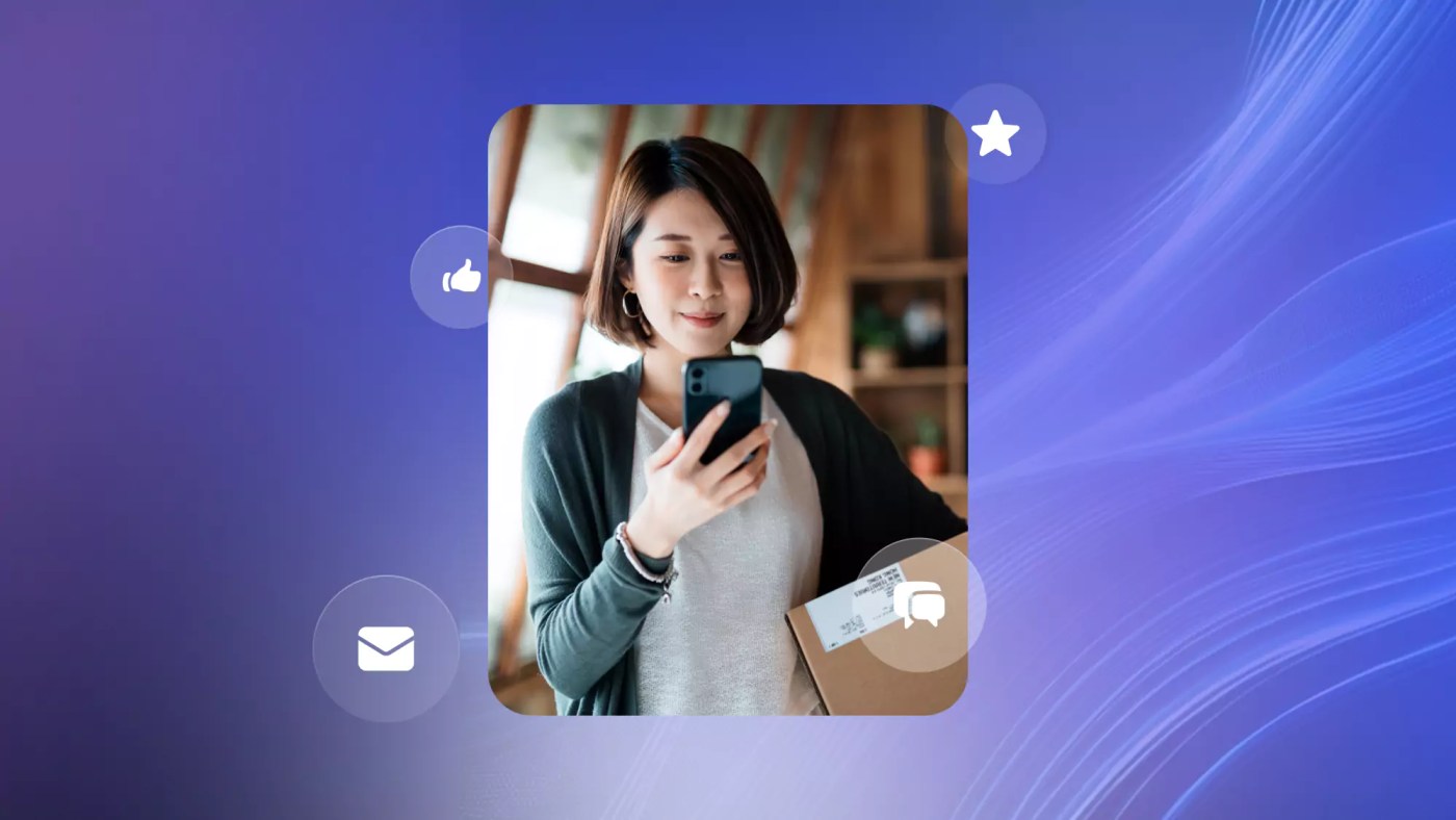 Someone looks at a phone while holding a box, indicating they are using an omnichannel communication platform.