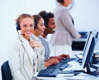 Smiling young executives sitting with headsets and using computer